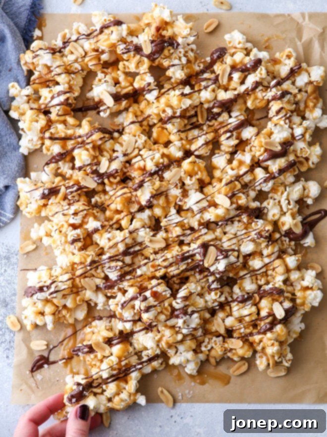 A large bowl of homemade chocolate caramel corn with peanuts, dark chocolate drizzle, and flaky salt, ready for serving at a holiday party.