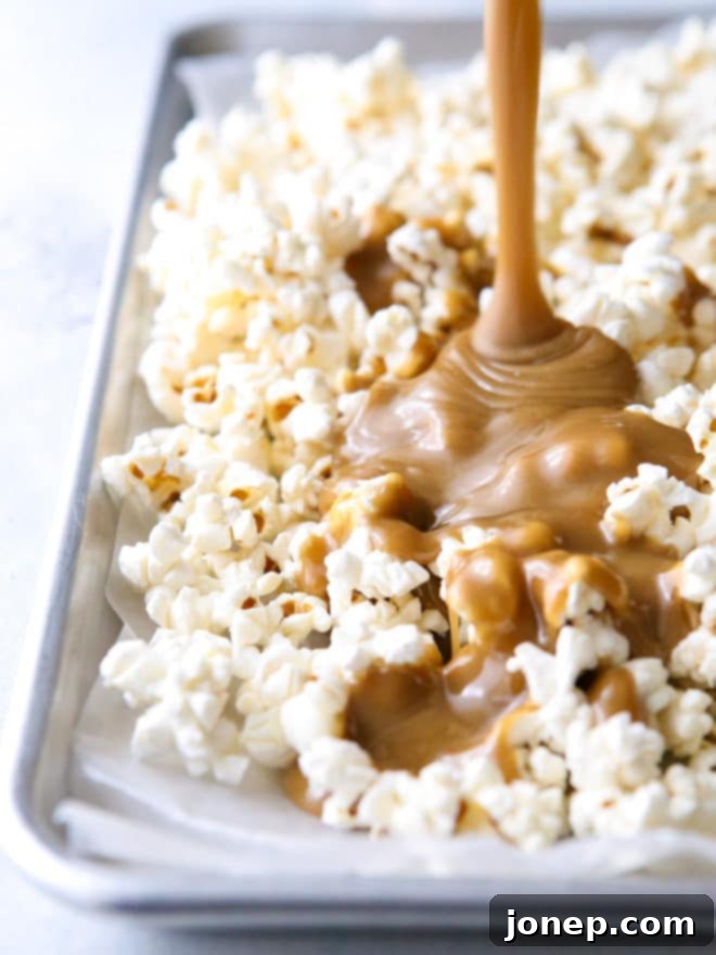 The process of coating popcorn and peanuts with a thick, golden caramel sauce in a large bowl, showing the rich texture and even distribution.