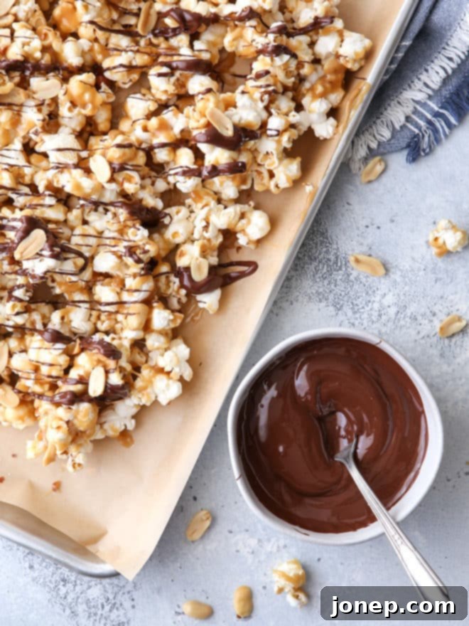 A close-up shot of a hand reaching for a piece of chewy chocolate caramel corn, highlighting its glistening caramel and chocolate textures.
