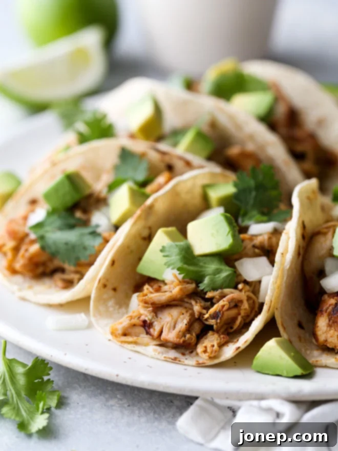 These easy Mexican street tacos filled with spiced shredded chicken, chopped onions, avocado, and cilantro are sure to become a favorite with everyone!