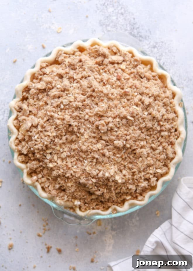 Assembled Dutch apple pie with golden brown crumb topping, ready to go into the oven