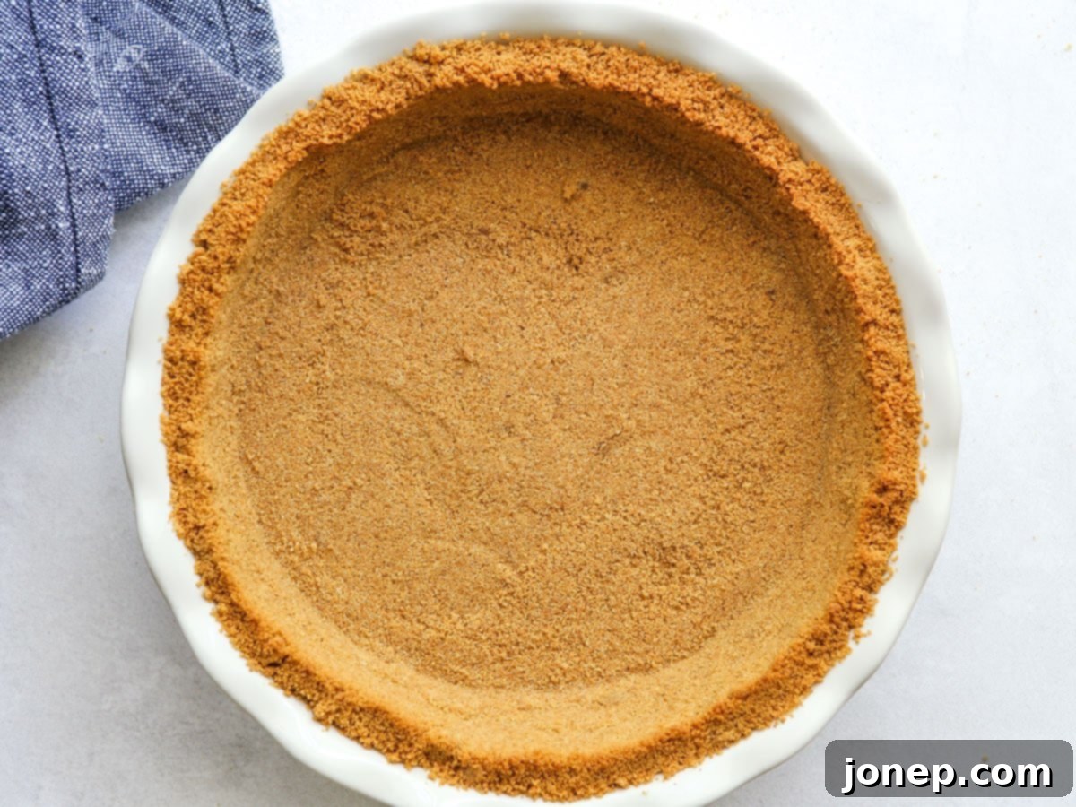 A golden-brown graham cracker crust perfectly pressed into a pie pan, ready for the filling.