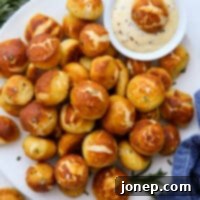 Homemade cheddar and rosemary pretzel bites with a side of honey mustard dip.