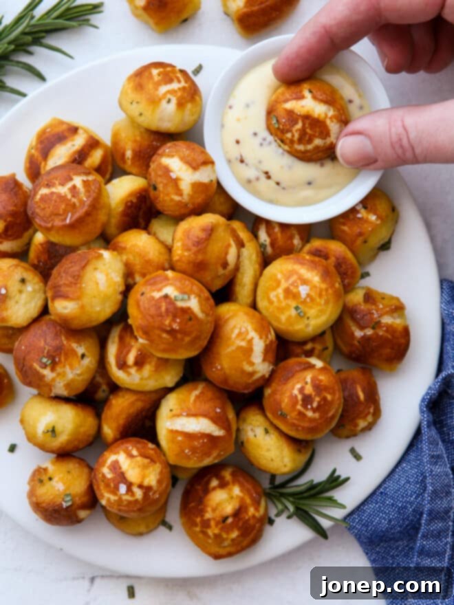 Close-up of golden brown cheddar and rosemary pretzel bites, perfectly salted, ready to be dipped.