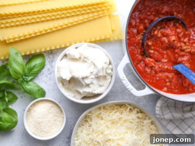 A close-up view of the uncooked layers of classic meat lasagna in a baking dish. You can see the distinct layers of pasta, homemade meat sauce, creamy ricotta cheese, and shredded mozzarella before it goes into the oven.