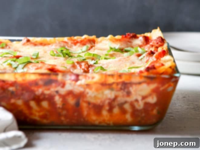A delicious whole classic meat lasagna, baked to perfection and garnished with fresh basil. It's presented beautifully in a baking dish, ready to be sliced and served.