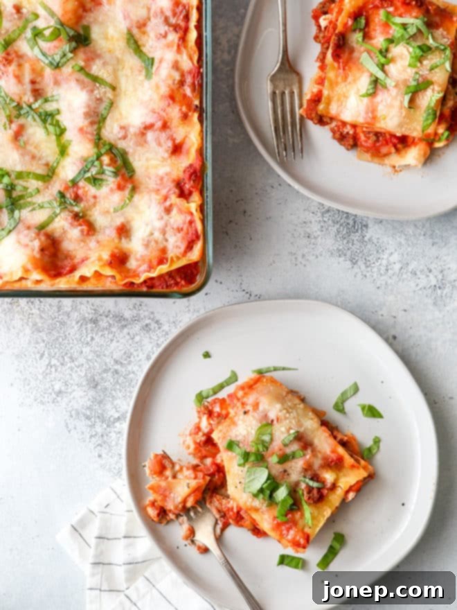 A beautiful top-down view of a classic meat lasagna, garnished with fresh basil and ready to be served. The golden-brown cheese topping is visible, along with the rich, meaty layers underneath.