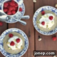 Top-down view of a bowl of homemade pistachio pudding with whipped cream and raspberries