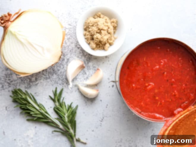 ingredients for easy homemade marinara sauce, including canned tomatoes, onion, garlic, and fresh herbs