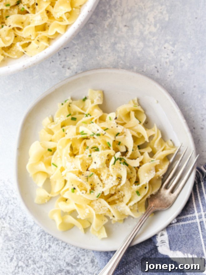 Simple buttered noodles are a quick and easy side dish, close up shot in a serving bowl with fresh herbs and cheese