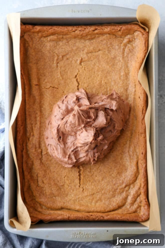 A close-up of a plate of perfectly cut peanut butter blondies, showing their soft texture and generous layer of chocolate buttercream frosting.