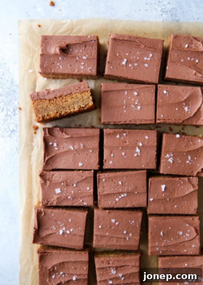 A stack of perfectly cut, soft peanut butter blondies with chocolate frosting, glistening and ready to be enjoyed.
