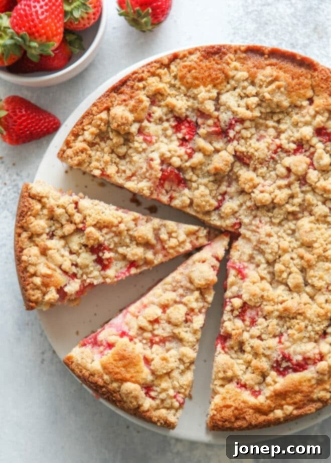A slice of strawberry rhubarb coffee cake with a streusel topping, perfect for breakfast or brunch.