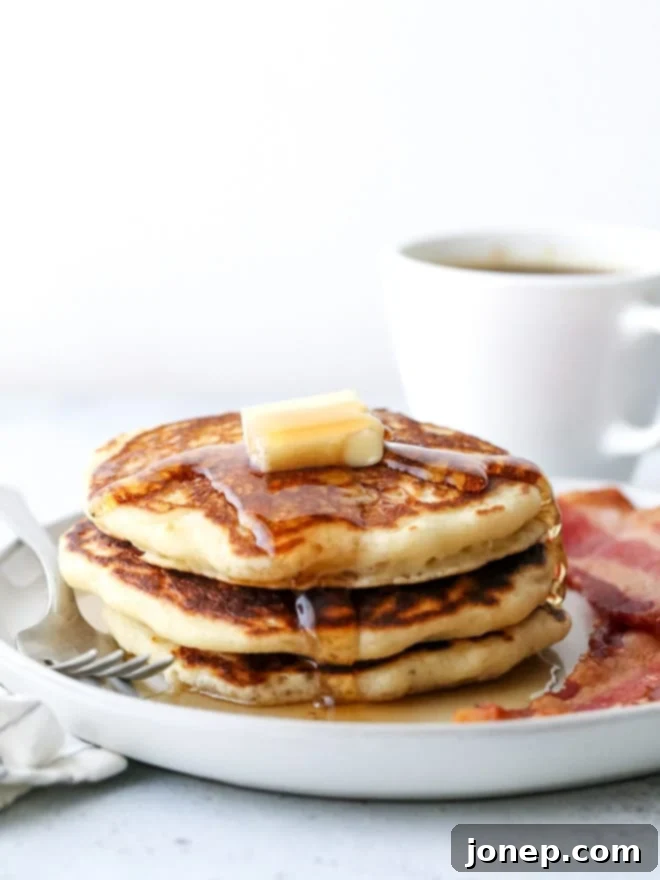 When to Use Baking Powder or Baking Soda 5 Fluffy stack of buttermilk pancakes with syrup and berries, emphasizing their light and airy texture.