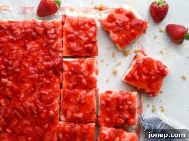 Close-up of a serving of no-bake strawberry cheesecake bars, showing layers of crust, filling, and strawberry topping.