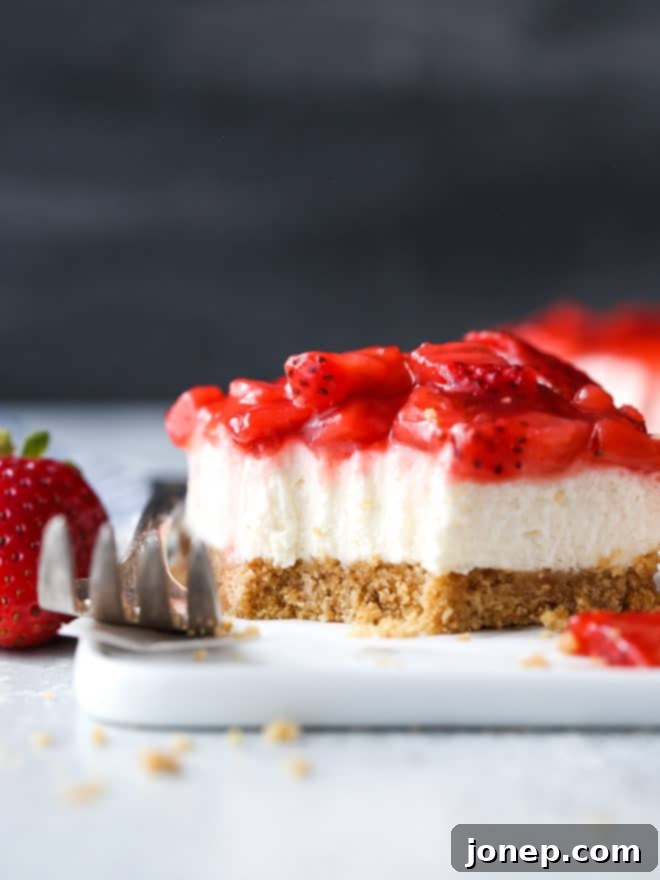A neatly sliced no-bake strawberry cheesecake bar on a serving platter.