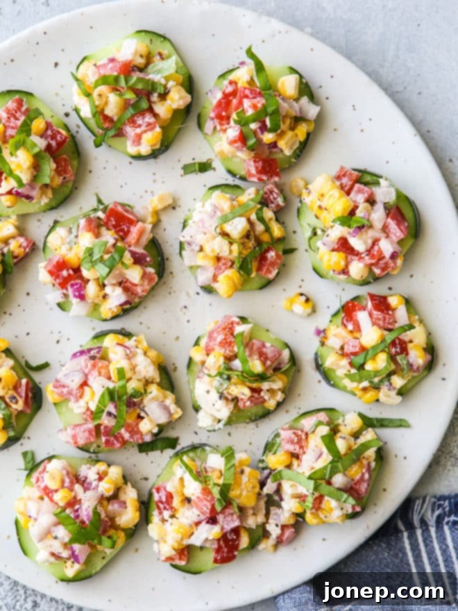 Individual cucumber bites topped with a corn and red pepper salad filled with feta, basil, and a creamy dressing.