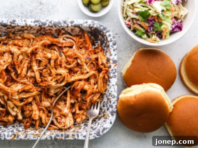 Assembling pulled BBQ chicken sandwiches with coleslaw and pickles