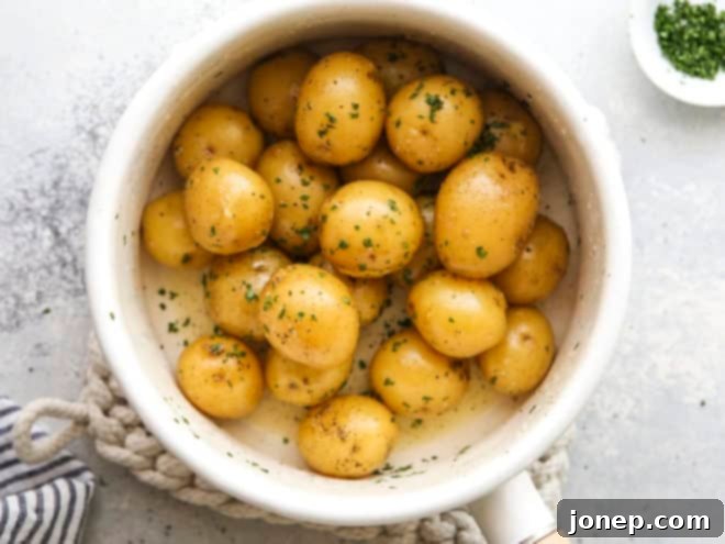 Buttery boiled potatoes in a deep cooking pot, coated in golden melted butter and ready to be served as a delightful side dish.