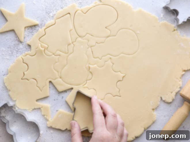 cutting out rolled cookie dough with christmas cookie cutters