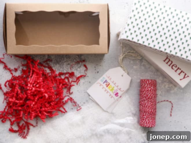 Various cookie packaging supplies laid out on a table, including shipping boxes, plastic bags, ribbons, and decorative crinkle paper, ready for use.