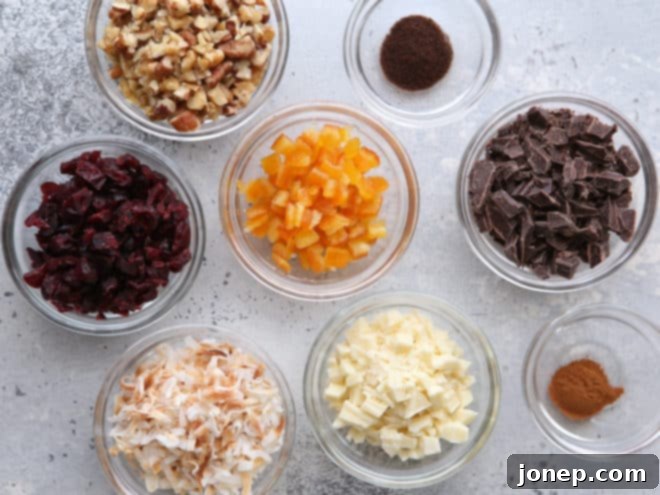 Assortment of shortbread cookie mix-ins, including chopped dark chocolate, white chocolate, pecans, dried cranberries, and candied orange peel.