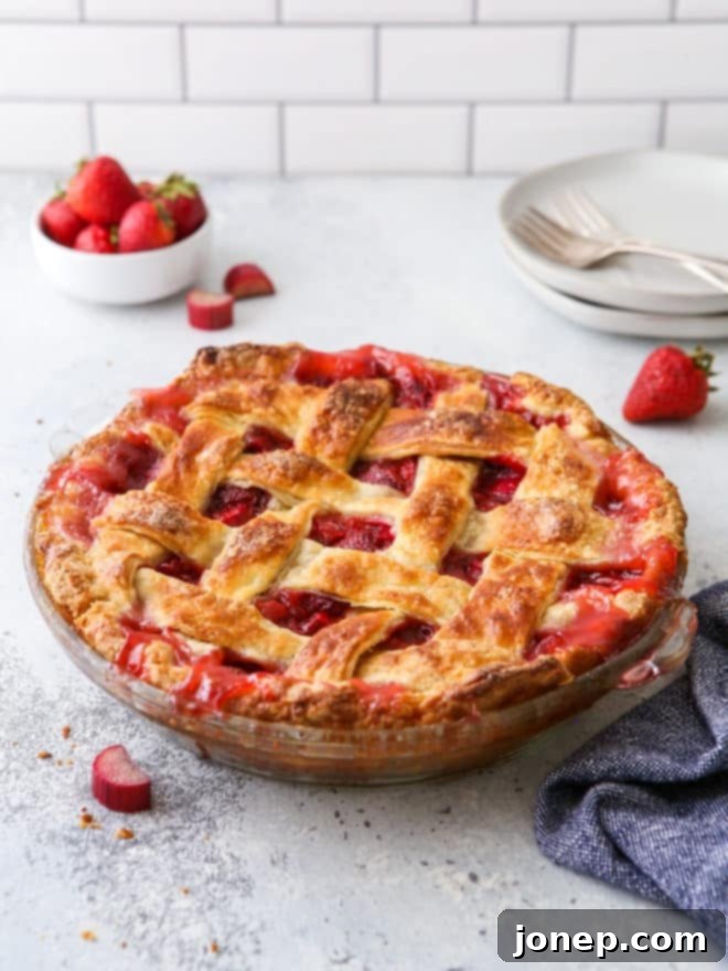 Sweet and Tangy Strawberry Rhubarb Pie 2 strawberry rhubarb pie on table with stack of plates