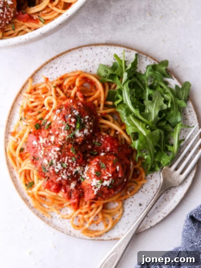 spaghetti and meatballs on a plate with salad
