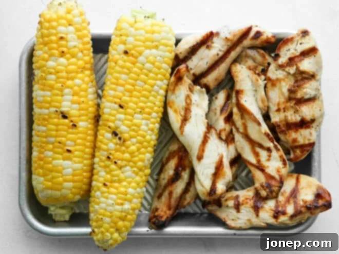 Grilled corn on the cob and seasoned chicken breasts on a grill