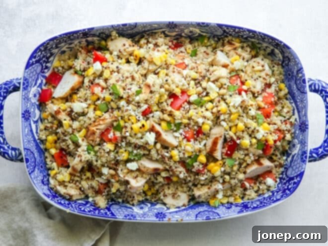 Tossed grilled chicken quinoa salad in a blue serving dish