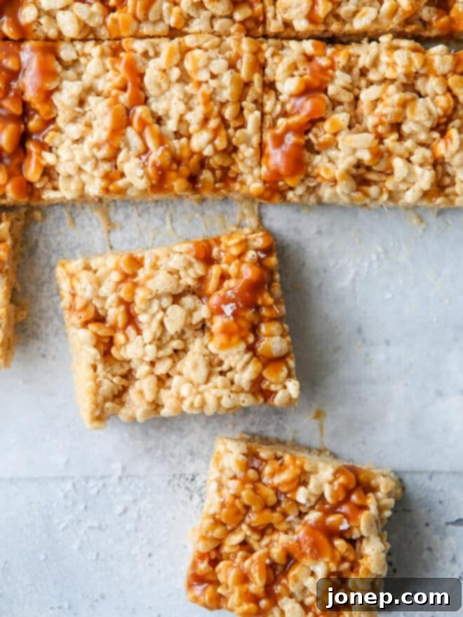 Close-up of squares of brown butter salted caramel rice krispie treats, showing their gooey texture and caramel swirls.