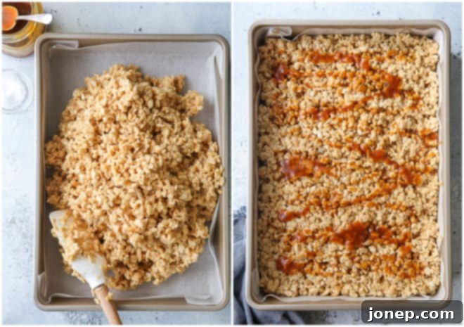 The rice krispie treat mixture being gently pressed into a 9x13 inch pan.