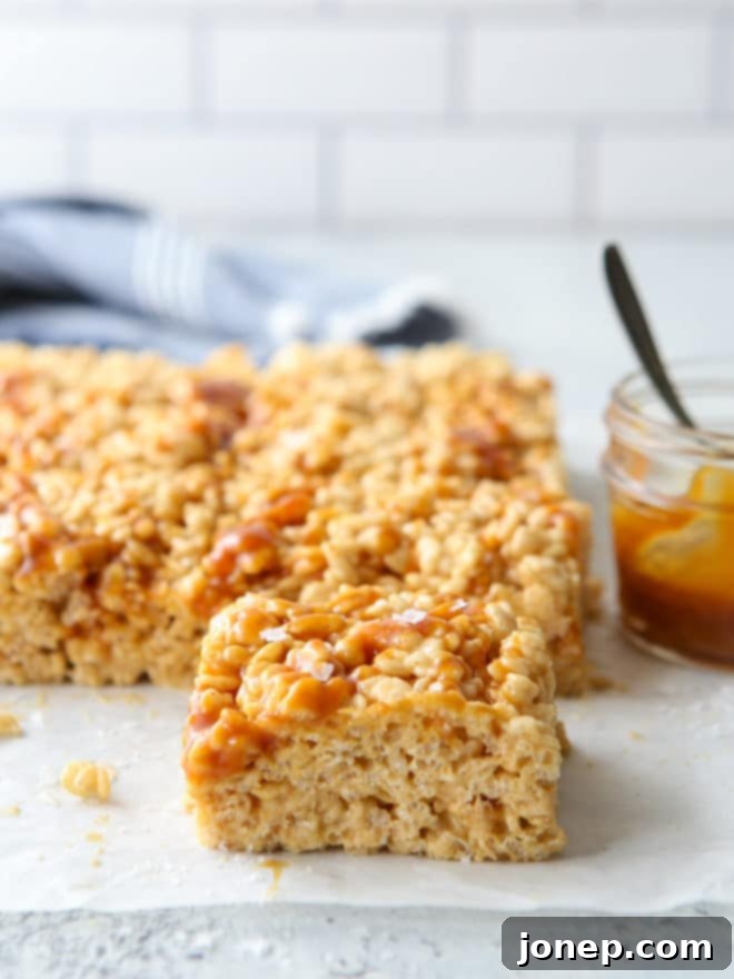 Side view of multiple brown butter salted caramel rice krispie treats, showing their height and layers.