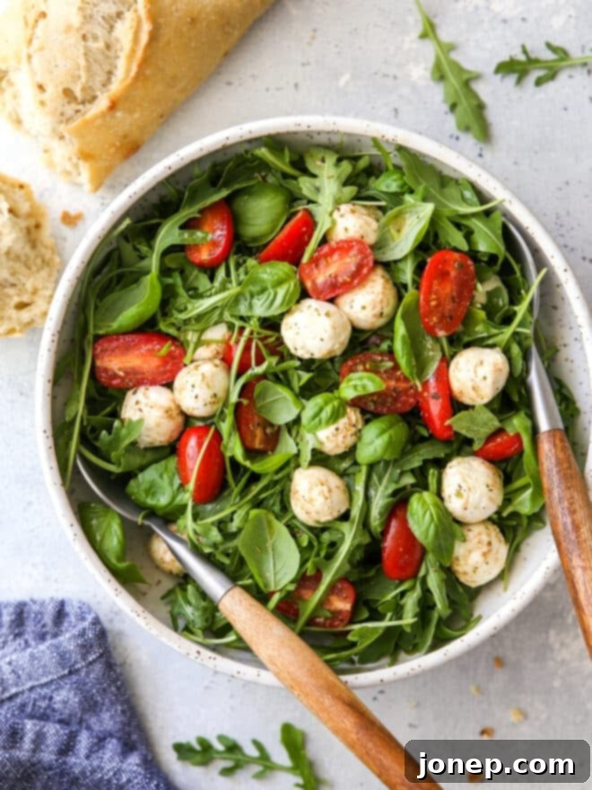 arugula caprese salad in a bowl with bread on the side