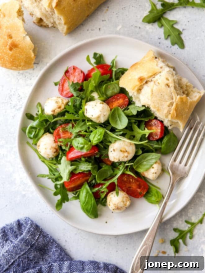 arugula caprese salad on a plate with a slice of bread