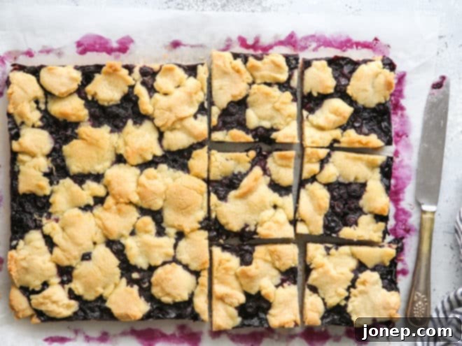 Berry Bliss Bars 6 Freshly baked blueberry pie bars being sliced into individual portions on a cutting board, ready to serve.