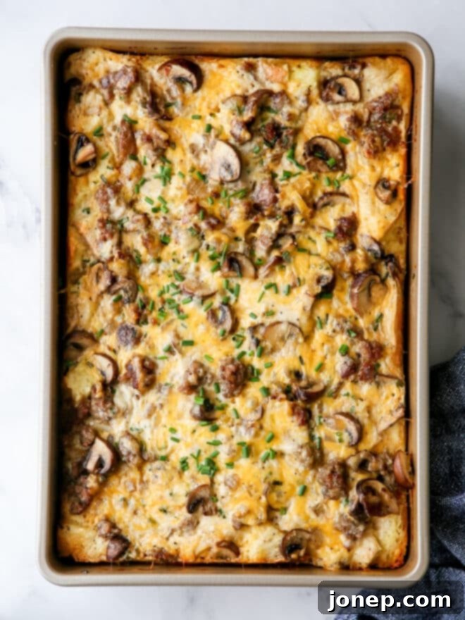 A baked dish of golden brown sausage and mushroom breakfast casserole, hot from the oven.