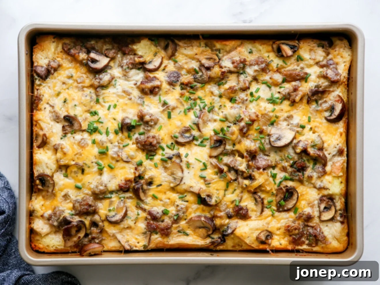 A beautifully baked sausage and mushroom breakfast casserole, golden brown and puffed, ready to be served.