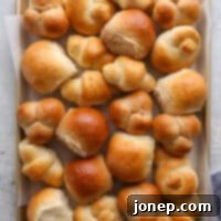 Mastering the Art of Dinner Rolls 15 a sheet pan filled with different shapes and flavors of dinner rolls