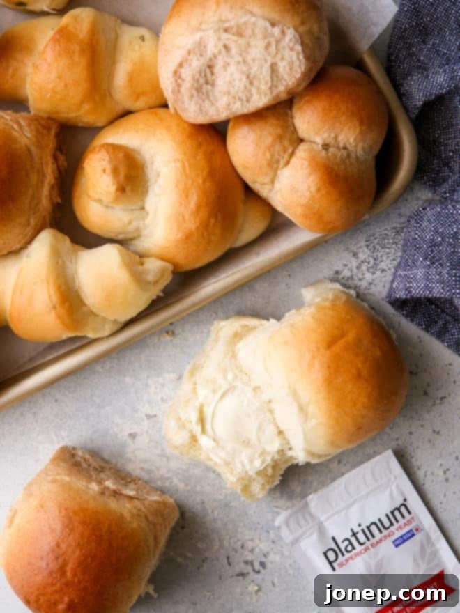 A golden brown, freshly baked dinner roll sliced open with a pat of butter, alongside a packet of Red Star Yeast, emphasizing the quality ingredients.