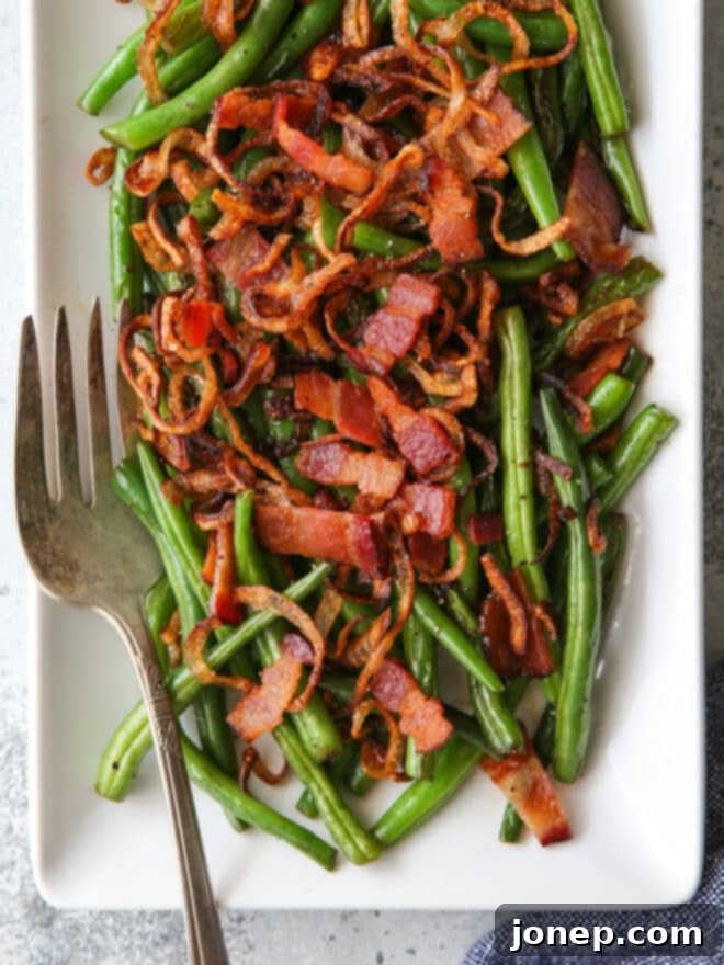 closeup of green beans with crispy shallots and bacon on a platter with fork