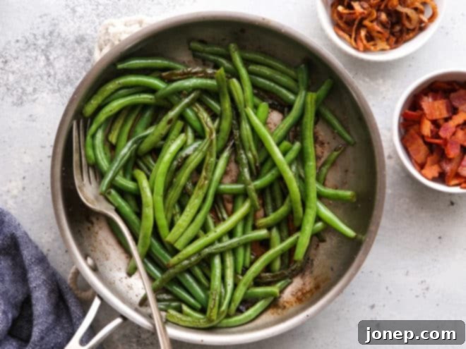sauteed green beans in pan with bacon and shallots on side