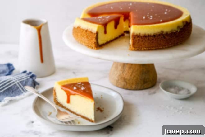 slice of salted caramel cheesecake on a plate with cake stand in background