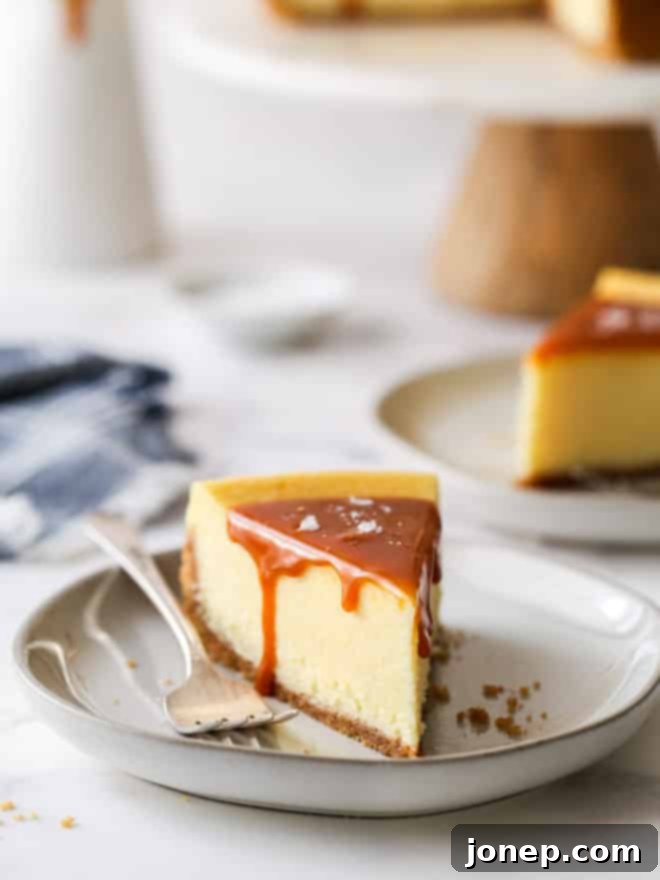 closeup of slice of salted caramel cheesecake on a plate with cake stand in background