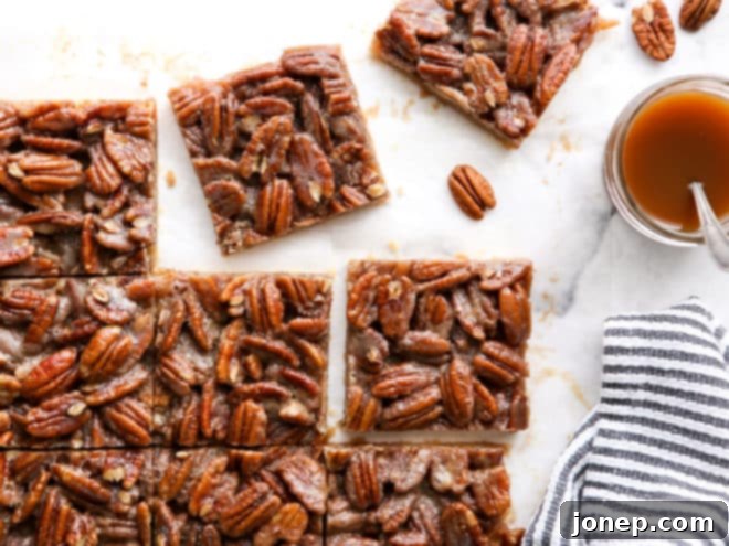 pecan pie bars cut into squares with jar of caramel