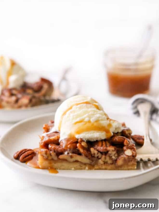 closeup of pecan pie bar with ice cream and caramel drizzle on a plate
