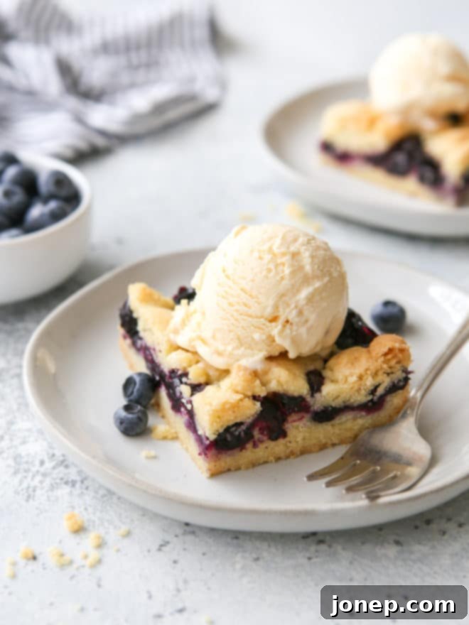 blueberry pie bars with a scoop of ice cream on a plate
