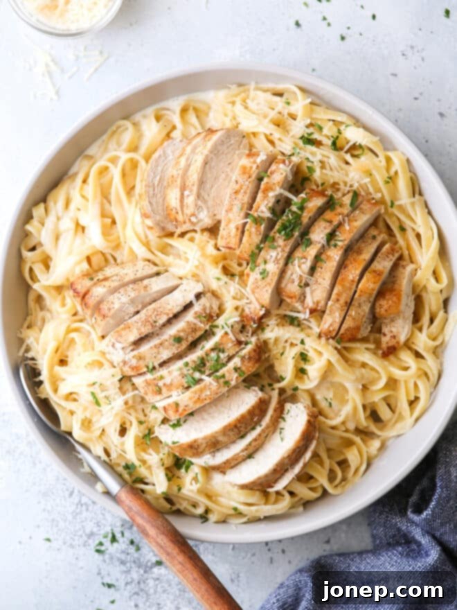 A beautifully plated bowl of creamy chicken fettuccine alfredo, garnished with fresh parsley.