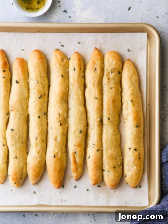 Warm, baked no-knead breadsticks with garlic herb butter, fresh from the oven