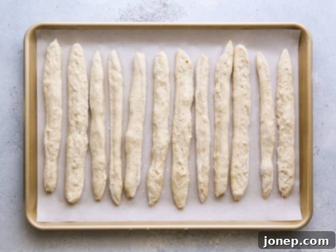 Breadstick dough strips arranged on a parchment-lined baking sheet, ready for baking